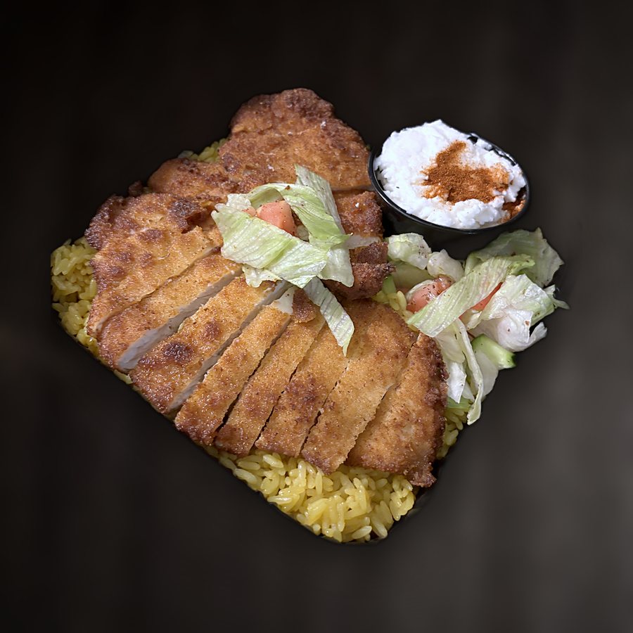 Sliced breaded chicken cutlet over yellow rice with salad and ranch